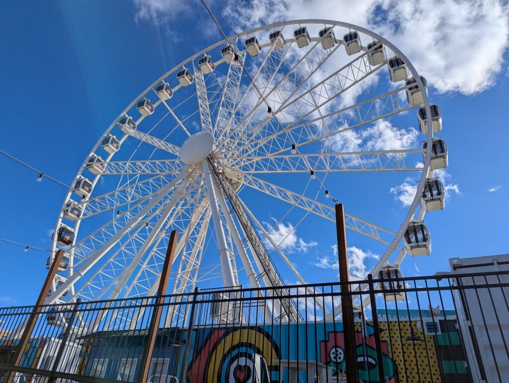 View of the KC Wheel at Kansas City’s Pennway Point, a large Ferris wheel with climate-controlled gondolas, offering scenic city skyline views at night.