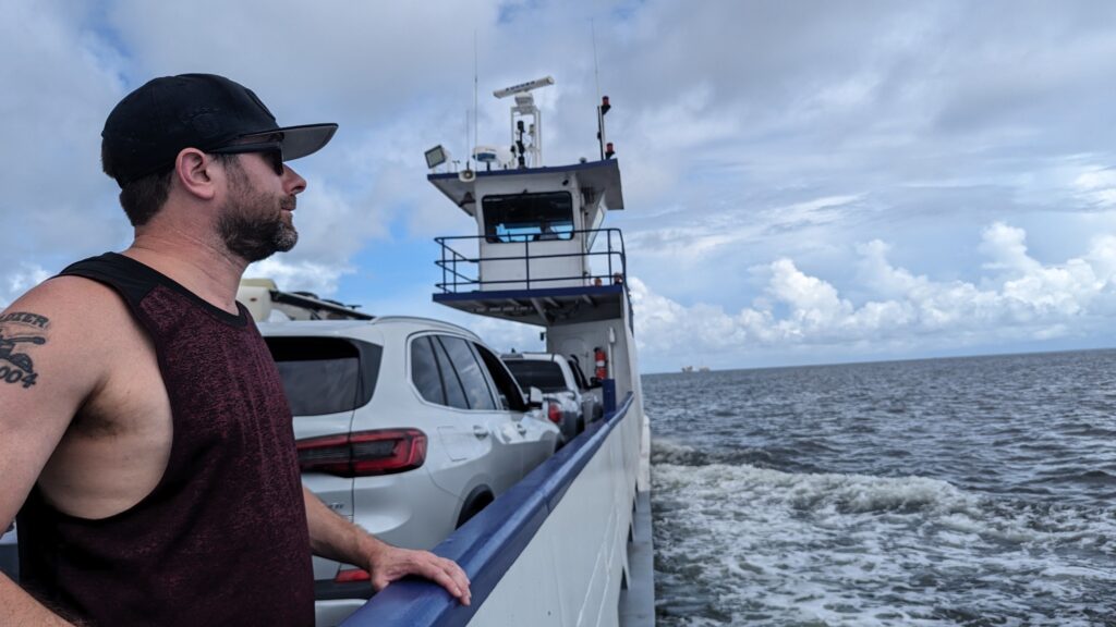 Scenic view from the Mobile Bay Ferry in Alabama, featuring calm waters, blue skies, and a distant shoreline.