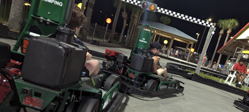 Go-karts racing down the multi-level wooden track at The Track in Gulf Shores, Alabama, with excited drivers.