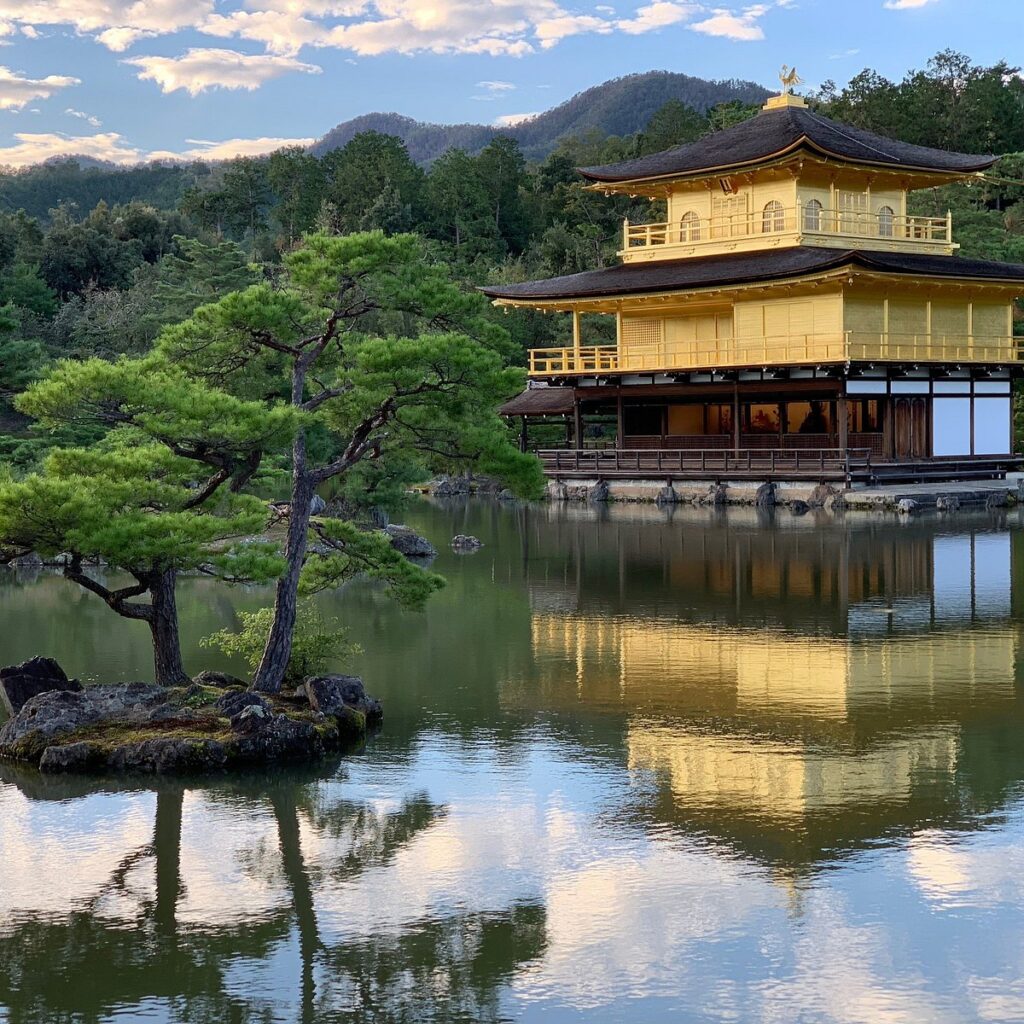 Number 2 of the top 5 travel destinations, a peaceful pond in Kyoto, Japan, reflecting a traditional Japanese house surrounded by vibrant greenery and tranquil gardens.