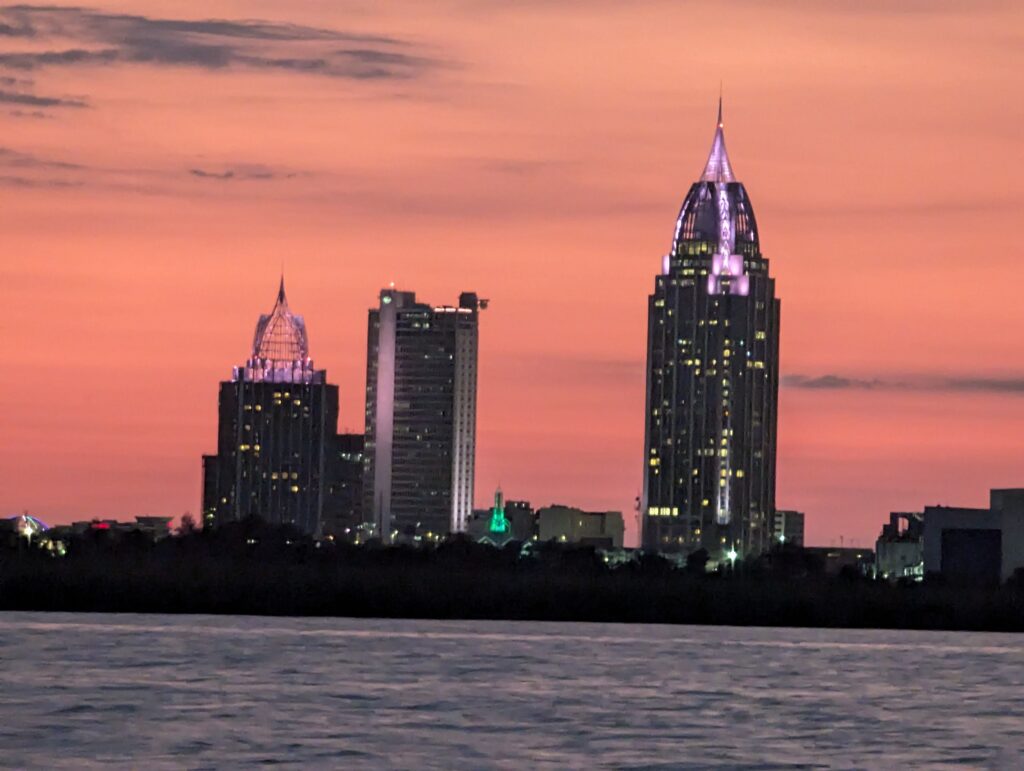 The glowing city lights of Mobile, Alabama, as seen from the deck of the Perdido Queen dinner cruise ship at night.