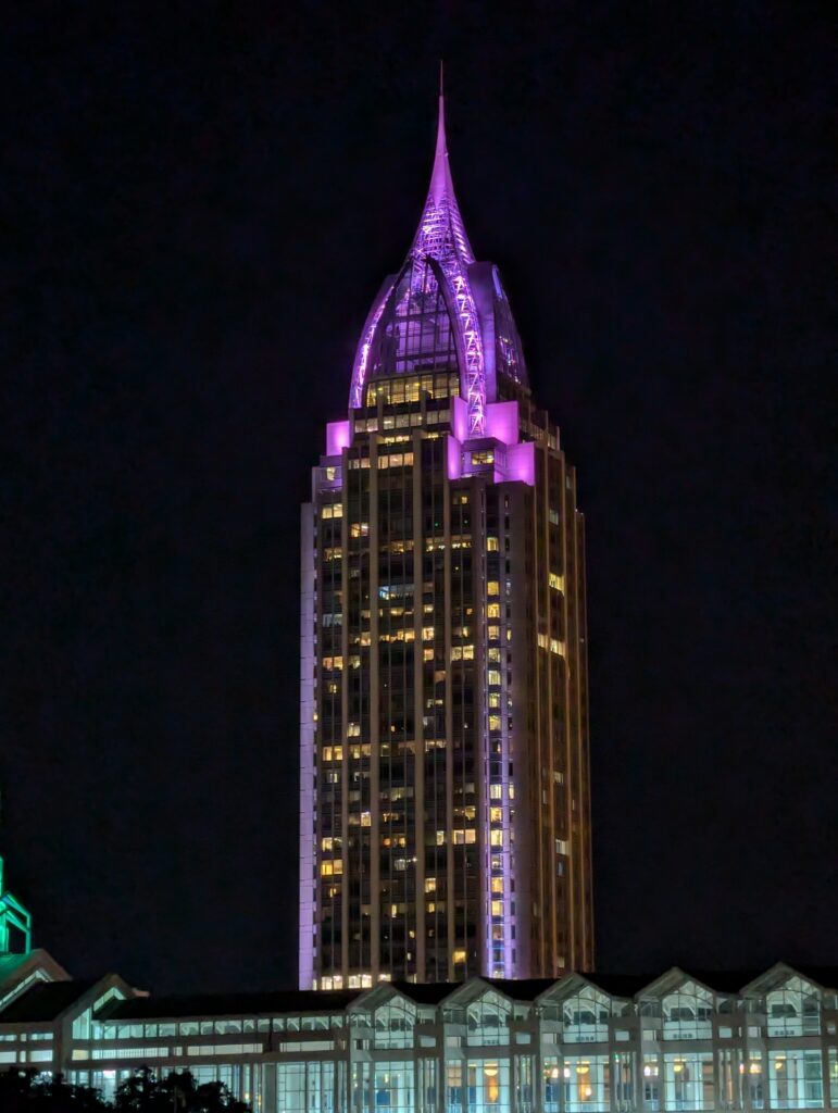 The glowing city lights of Mobile, Alabama, as seen from the deck of the Perdido Queen dinner cruise ship at night.