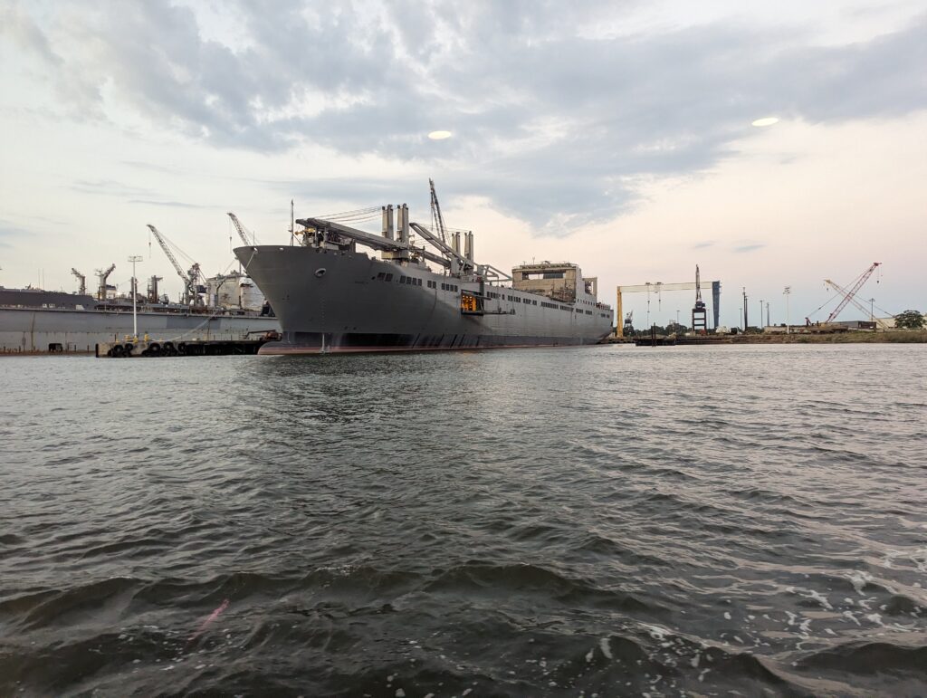 A naval ship anchored in Mobile Bay, Alabama, with its imposing structure standing out against the calm waters.