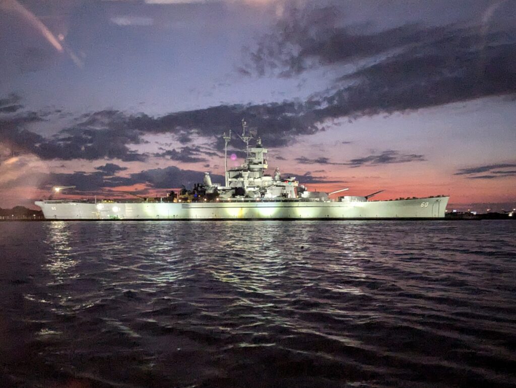 A naval ship anchored in Mobile Bay, Alabama, with its imposing structure standing out against the calm waters.