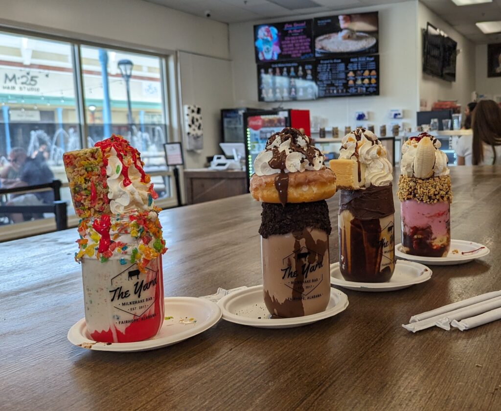 Over-the-top milkshakes from The Yard Milkshake Bar in Gulf Shores, Alabama, topped with whipped cream and colorful desserts.