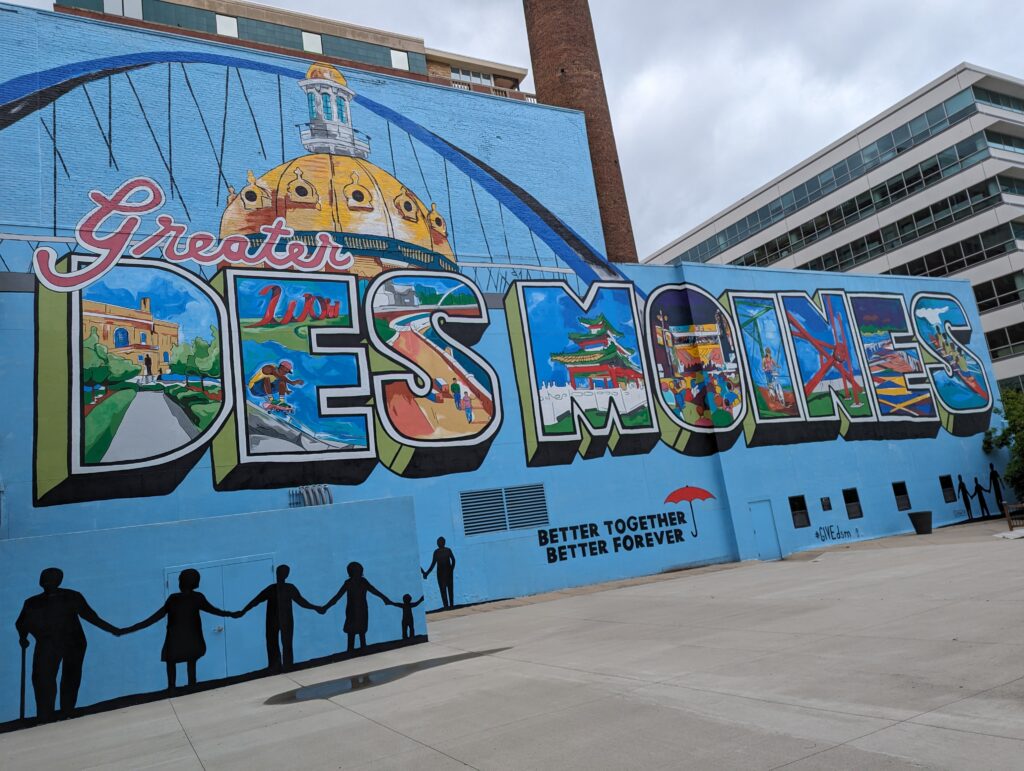 Colorful Greater Des Moines mural featuring iconic landmarks and vibrant scenes, showcasing the community spirit and culture of the city.